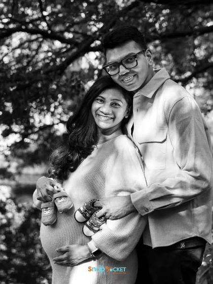 A happy black and white portrait with a special detail. This couple is holding up two pairs of tiny baby shoes, hinting that they might be expecting twins! It's a fun and creative announcement idea.