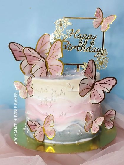 A pretty cake with a pink and grey watercolor effect, adorned with pink butterflies.