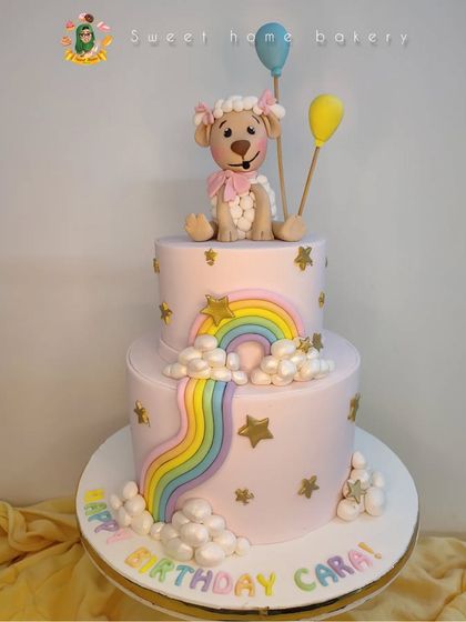 A sweet little sheep for a sweet little girl. This two-tiered cake for Cara's birthday is decorated with a pastel rainbow, fluffy clouds, and golden stars. The adorable, hand-sculpted sheep topper with her balloons makes it a truly gentle and dreamy design.