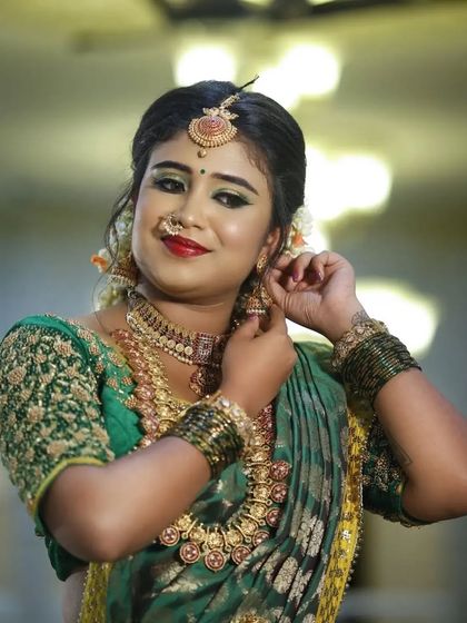 A close-up of the bride adjusting her jhumka, showing the detail of the earring and the matching necklace.