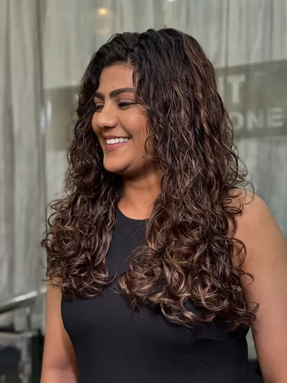 Proof that curls and color are a magical combination. Here, we enhanced natural curls with subtle highlights to create depth and dimension. The result is healthy, defined curls that pop with vibrancy and shine.