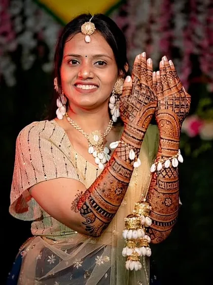 A happy bride showing off her mehandi stain. The design features a mix of geometric and floral patterns, and the rich color demonstrates the quality of the henna used.