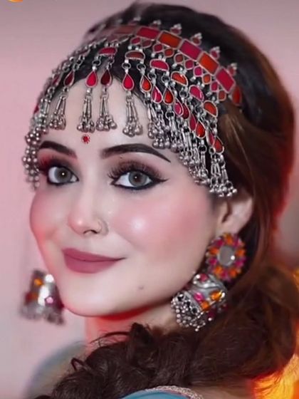 A model wearing a vibrant red and silver oxidised mathapatti with matching earrings. The colorful enamel work makes this set truly unique.