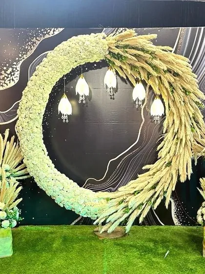 A bohemian-inspired photo booth featuring a large crescent of white florals and dried pampas grass. The design is modern, earthy, and incredibly chic.