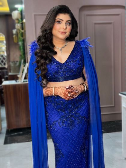 The full view of this dramatic look. The cape sleeves and the bold color of the dress are complemented by equally glamorous makeup and hair.