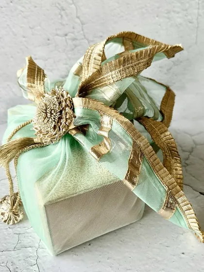 A beautifully wrapped gift box, showcasing my elegant packaging style. The mint green box is tied with a golden gota-patti style wrap, perfect for any festive or wedding gift.