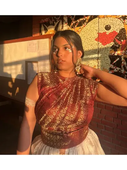 A closer look at the draped top and the creative makeup for this fusion look. The styling extends to the face gems and armlet, tying the whole theme together.