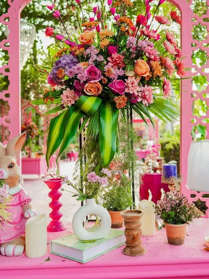 A close-up of the pink welcome desk, adorned with a massive floral arrangement, a cute rabbit figurine, and other whimsical details. Every corner is a feast for the eyes.