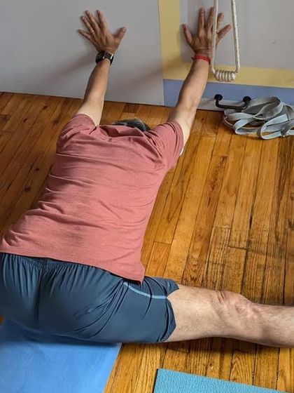 Practicing Hanumanasana (splits) against the wall. The wall provides a boundary to help deepen the stretch and maintain squareness in the hips.