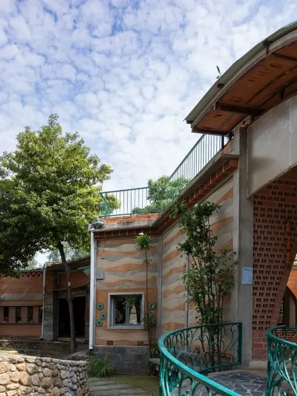 The exterior of a building should tell a story of its materials. At the Foothill Learning Centre, the layered patterns of a rammed earth wall stand beside the rhythmic texture of hollow clay blocks, showcasing a design rooted in nature.