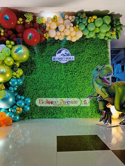 A thrilling Jurassic World dinosaur theme, perfect for adventurous kids. This setup features a large T-Rex cutout, a grass-like backdrop, and a volcanic color scheme for the balloon garland.