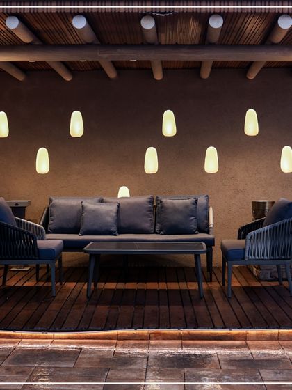 This outdoor seating area is a perfect blend of rustic and modern design. The wooden pergola, comfortable dark furniture, and soft, glowing pendant lights create a serene and stylish oasis.