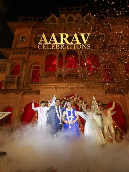 A spectacular finale for an anniversary celebration at Chomu Palace. The couple is showered with golden confetti as pyrotechnics light up the sky behind the magnificent palace.