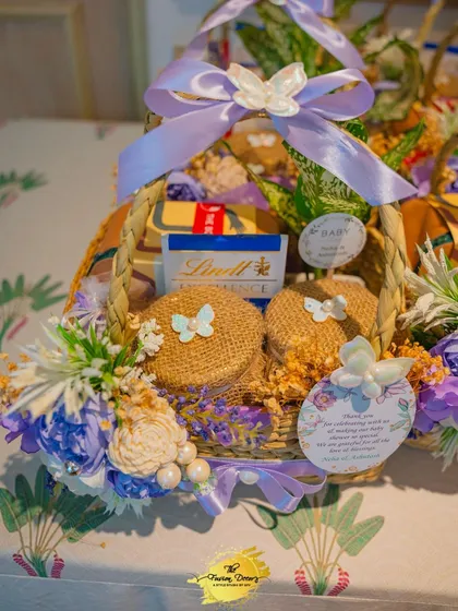 A beautifully crafted baby shower gift hamper. I love creating these personalized baskets, filled with treats and essentials, decorated with flowers and ribbons to match the event's theme.