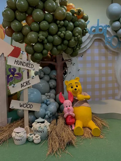 Pooh and Piglet sitting amongst hay bales and "hunny" pots, creating an adorable photo opportunity at the Hundred Acre Wood party.