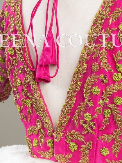 Grace in every detail. This pink net blouse features delicate leafy vines embroidered in gold and light green thread. The deep V-back and sheer sleeves add a touch of modern femininity.