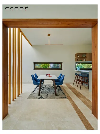 A view into the dining and kitchen area of the 'Framed House.' The interior is framed by a thick timber portal, creating a deliberate and picturesque composition that connects adjacent spaces.