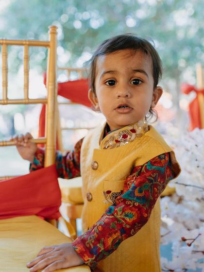 Another sweet shot from the Haldi ceremony. This little one looks absolutely charming in his custom-designed yellow Bundi and colorful printed kurta.