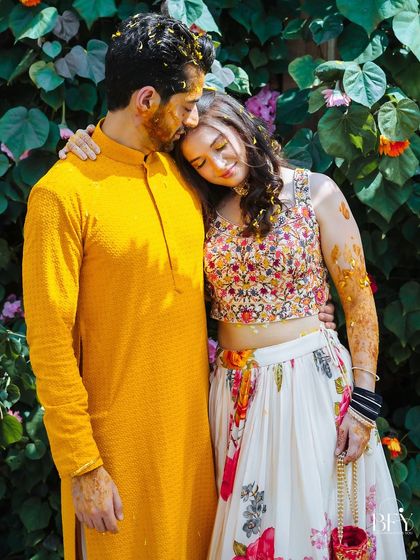 A quiet, tender moment as the groom rests his head on the bride's shoulder amidst the Haldi festivities.