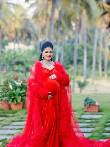 A full-length view of the stunning red velvet and tulle robe combination. This outfit is designed to make a statement in a beautiful garden or estate setting for your maternity photoshoot.