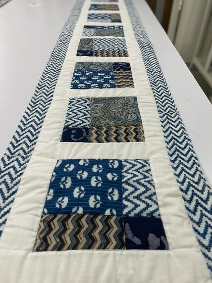 A table runner made with indigo-dyed fabrics in a patchwork design.