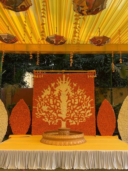 We created this beautiful 'Tree of Life' backdrop entirely from fresh marigold flowers. Paired with a traditional brass urli, this Haldi stage is a unique piece of floral art that celebrates our traditions.