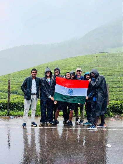 A group of friends holding the Indian flag in the rainy tea plantations of Munnar.