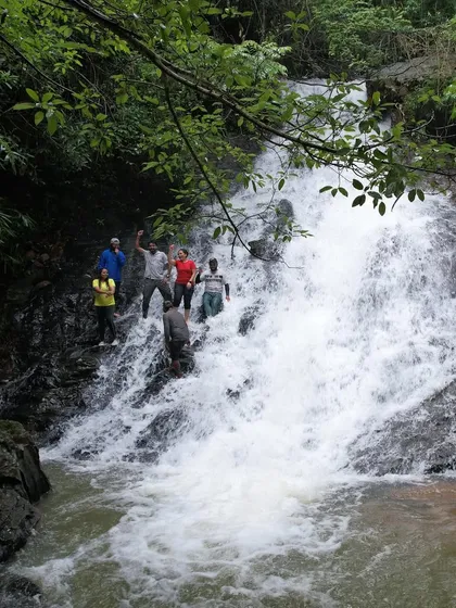 Trekkers dancing and enjoying themselves on the slippery rocks of a waterfall, a perfect example of the fun we have.