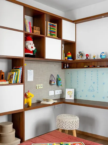 The kid's room in 'Gulmohar' features an elaborate study unit with a checkered pattern of open and closed storage, a pin-up board, and a glass writing surface.