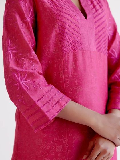 A detailed shot of a fuchsia kurta, highlighting the pintuck details and delicate self-embroidery on the sleeves and body.