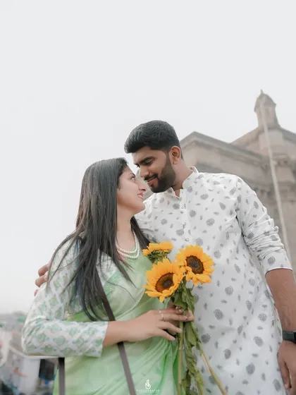 A lovely portrait with the couple looking at each other, framed against the sky and the top of the Gateway of India.