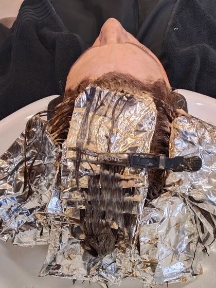 The hair colouring process at the wash basin. This step is crucial for toning and achieving the perfect final shade.