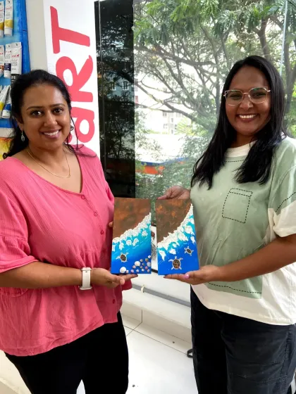 A couple with their finished canvas paintings of sea turtles. It's a fun split-canvas project that comes together to form one beautiful scene.