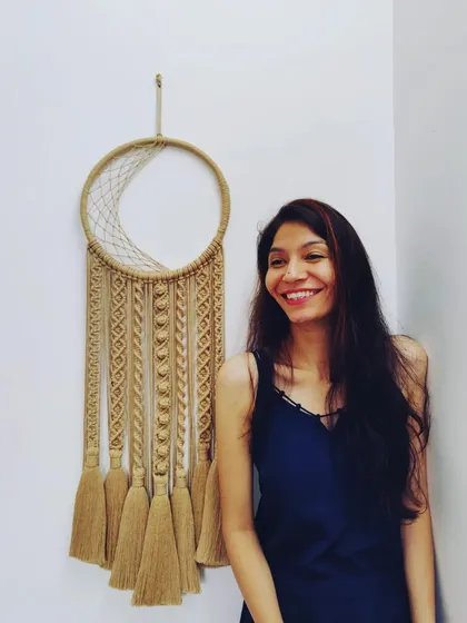 This is me with my first-ever macrame moon dreamcatcher. I always wanted to make one, and when a client asked for it as a wedding gift, I was so excited. It’s a big piece, 42 inches long on a 12-inch cane ring, and it represents the passion I put into every single knot.