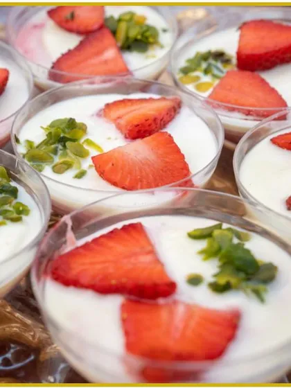 A light and creamy dessert served in individual glasses, topped with fresh strawberries and chopped pistachios. A perfect, elegant treat for any event.