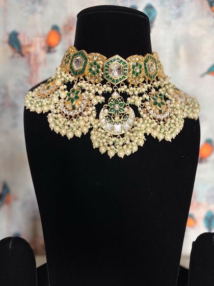 Embrace tradition with this beautiful Chand Kundan jewelry. The combination of green enamel, uncut stones, and pearl clusters gives it a classic yet fresh feel.
