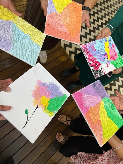 A circle of creativity. Five participants holding their vibrant, abstract texture paintings together.