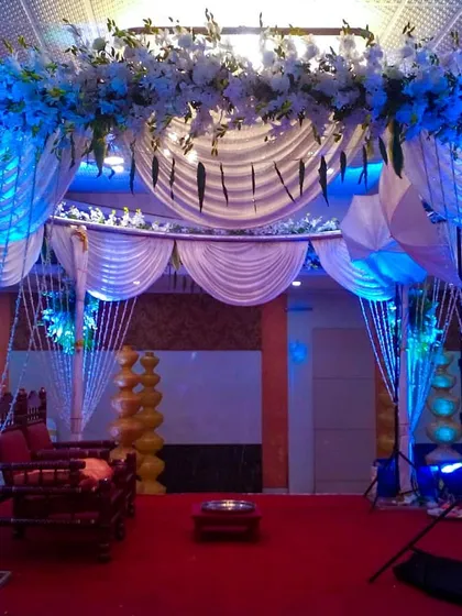 This is an entrance I created for a wedding mandap area. The rental decor includes the draped archway with blue lighting, crystal bead curtains, and floral toppers to welcome your guests.