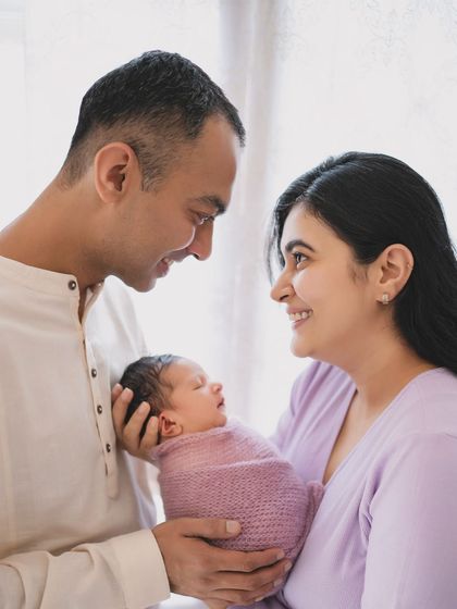 A tender moment between new parents and their sleeping baby.