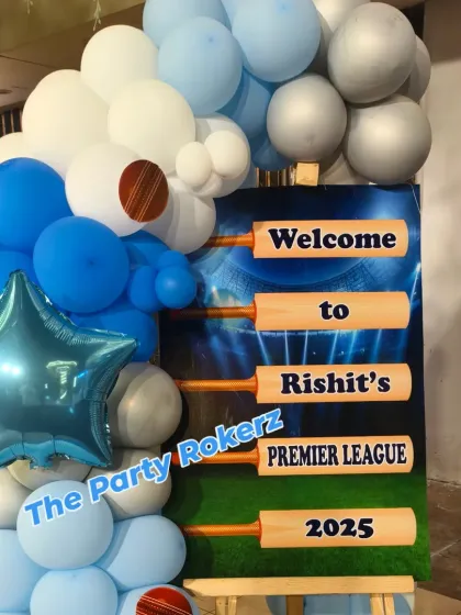The welcome sign for the cricket party, designed to look like cricket bats, surrounded by a blue and white balloon arrangement.