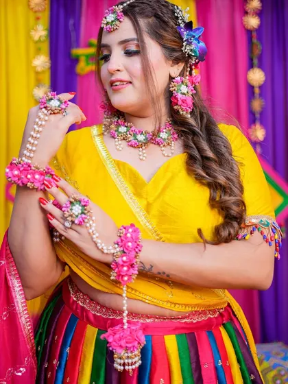 A vibrant and colorful Mehendi look. The rainbow lehenga and floral jewellery are paired with a fun, glowing makeup style.