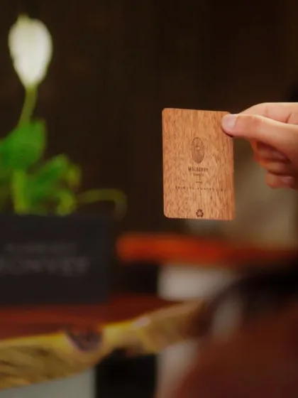 A guest holds our unique wooden room key card, a small detail that reflects our commitment to sustainability and a connection to nature.