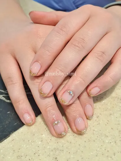 The cutest minimal jewel nails! This design combines a delicate gold glitter French tip with tiny, elegant jewels.