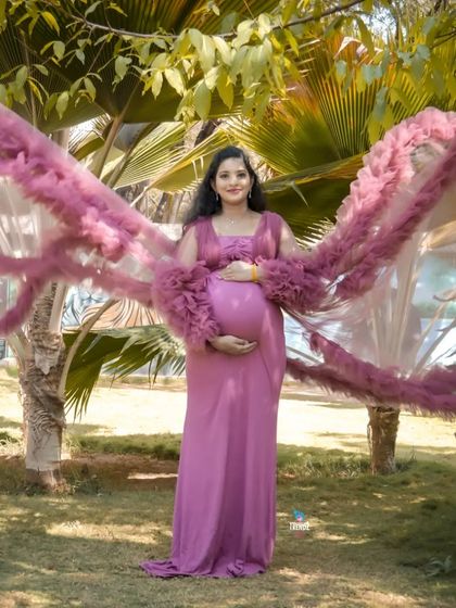 A full-length solo portrait in a garden, showcasing a dramatic gown with long, ruffled sleeves. This style of dress is perfect for creating high-impact, fashionable maternity photos.