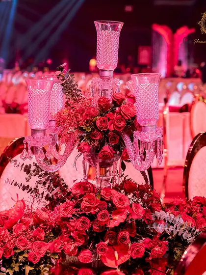 A close-up of the tablescape, featuring a crystal candelabra centerpiece overflowing with red roses and foliage. Every detail was chosen to reinforce the theme of passionate, luxurious romance.