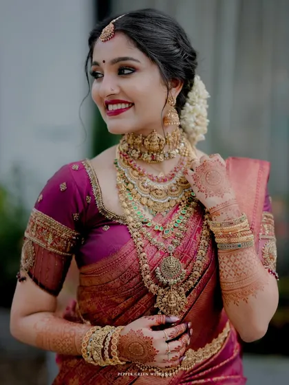 A stunning portrait of the bride in her rich magenta Kanjivaram saree, her smile and traditional gold jewelry radiating elegance.