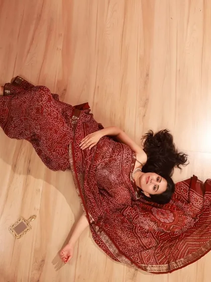 An artistic top-down shot that showcases the full spread of the maroon saree. This kind of creative composition is something I love to explore in my studio collaborations.