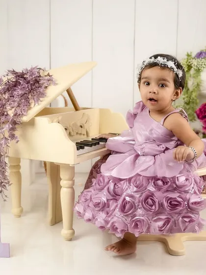 Taking a seat at the piano, this little girl is ready for her first birthday recital in a stunning rosette dress.