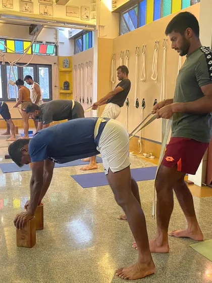 Using blocks and a belt, we work on opening the hamstrings and creating length in the spine for this athlete. This kind of targeted work with props helps address the specific tightness and imbalances that can result from repetitive movements in sports.