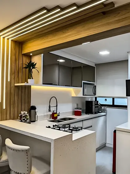 An excellent example of an open-concept kitchen design perfect for compact homes. This layout features a stylish breakfast bar with seating, seamlessly connecting the kitchen to the living area. The custom lighting feature adds a unique architectural element to the space.